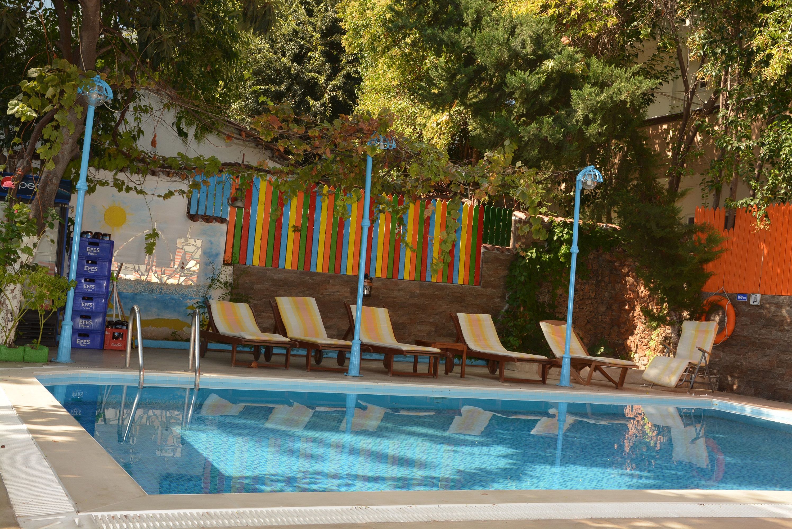 Una piscina con sillones de descanso y una valla colorida.