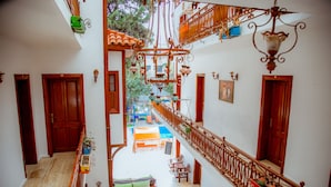 Un interior con varios niveles, barandillas de madera, una escalera central y vistas al exterior.