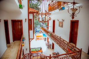 A multi-level interior with wooden railings, a central staircase, and a view of the outdoor area.