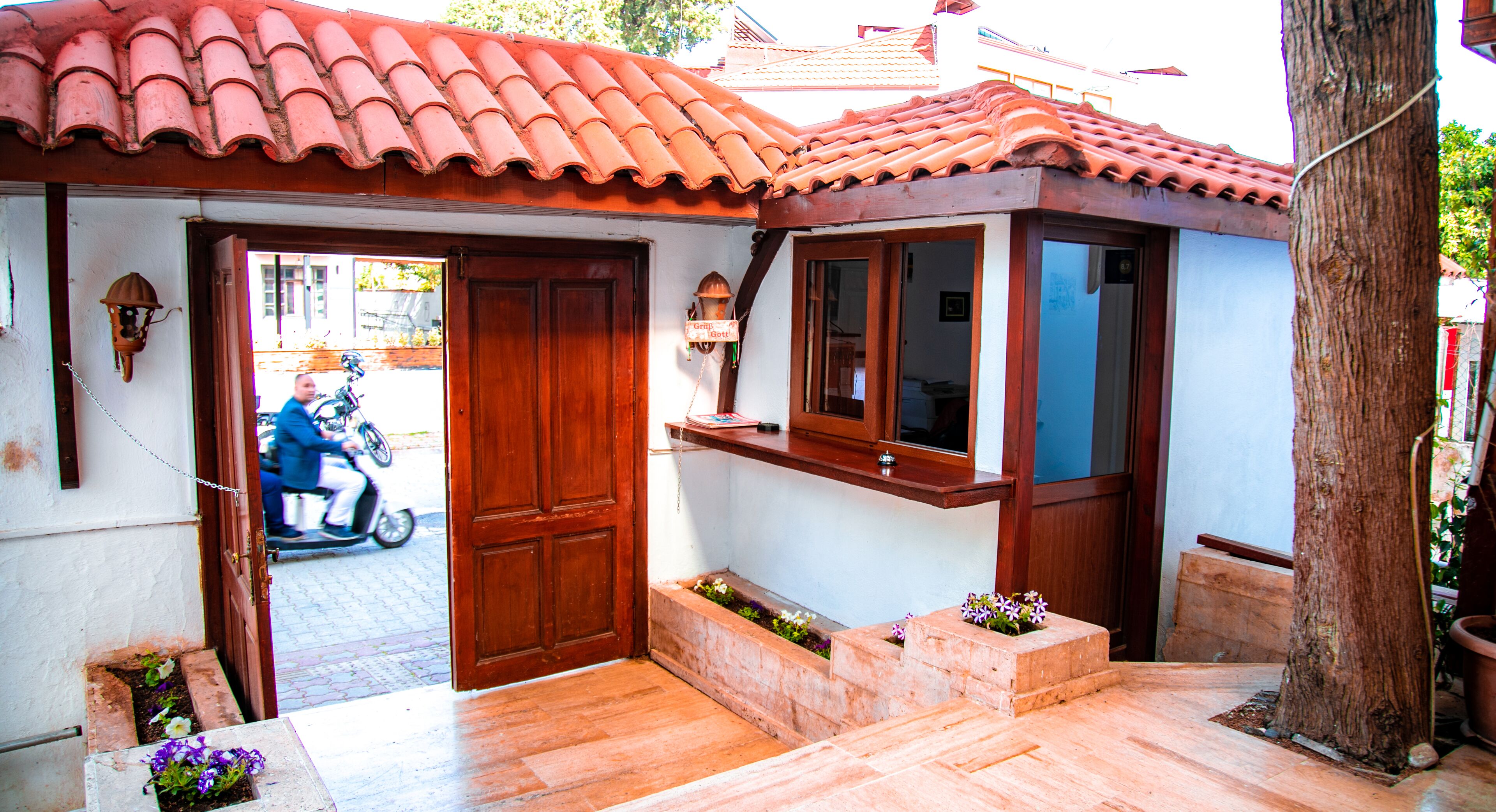 Ein Haus mit Ziegeldach, Holztür und einer kleinen Veranda mit Stufen zum Eingang.