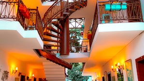 Un interior espacioso con una escalera espiral central, varios balcones y un alto techo con tragaluces.