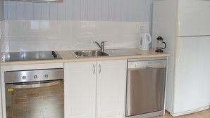 A compact kitchen with a stove, oven, sink, and dishwasher. - Twisted Gum Cottage (Ballandean)