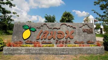 A sign with a fruit logo and text, surrounded by plants.