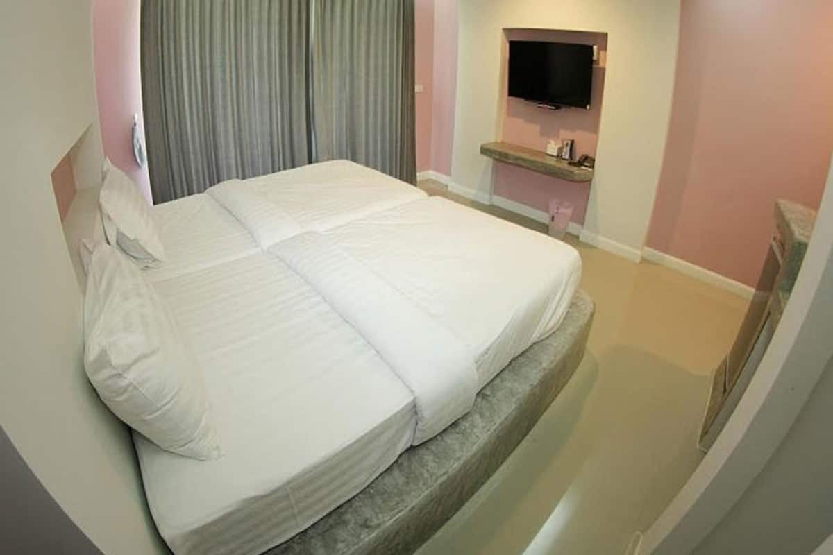 A hotel room with a large bed, a television mounted on the wall, and a small bedside table.