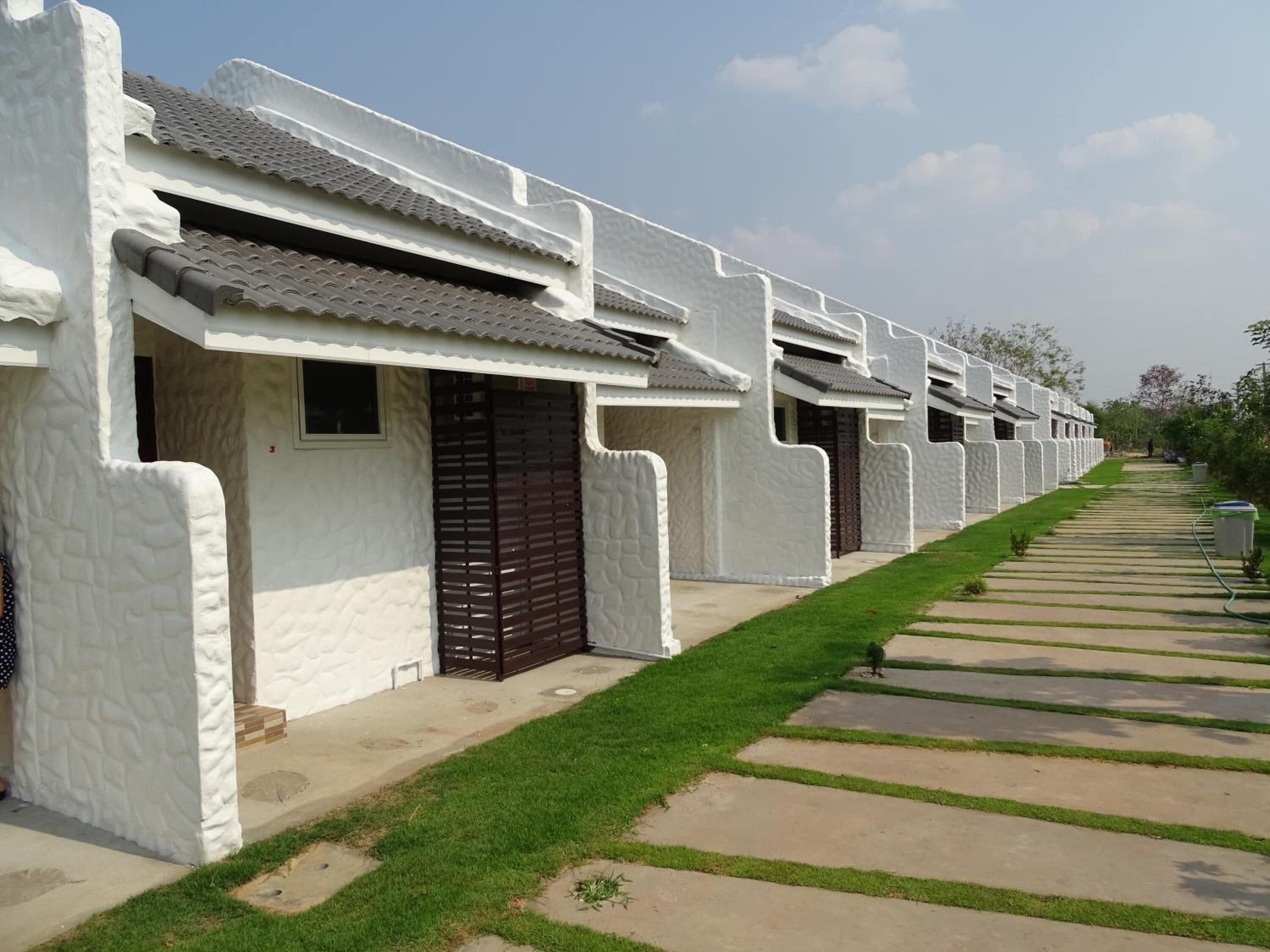 A row of white buildings with tiled roofs and a well-maintained lawn.