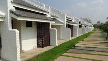 A row of white buildings with tiled roofs and a well-maintained lawn.