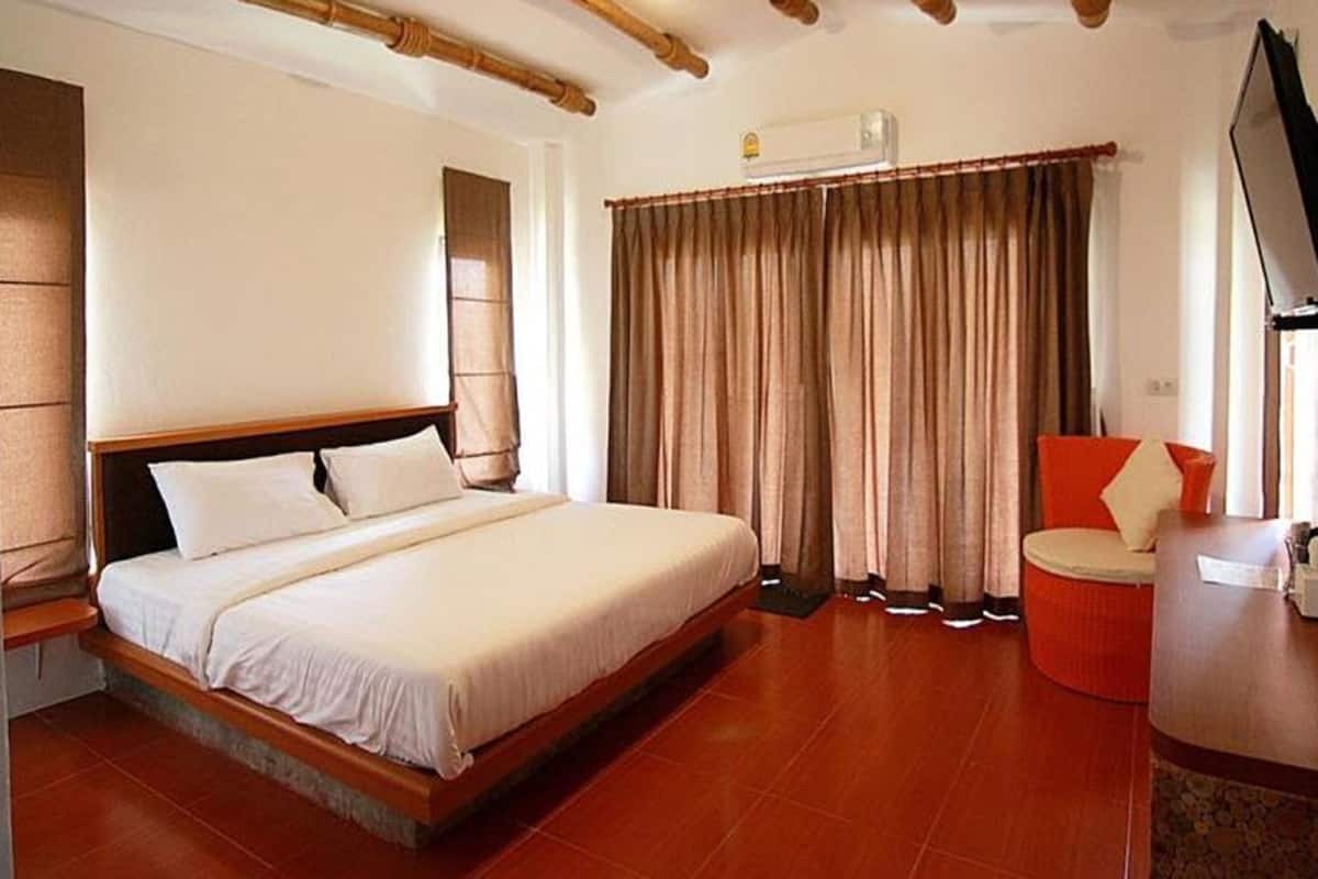 A hotel room with a large bed, a wooden headboard, a red chair, and a TV.