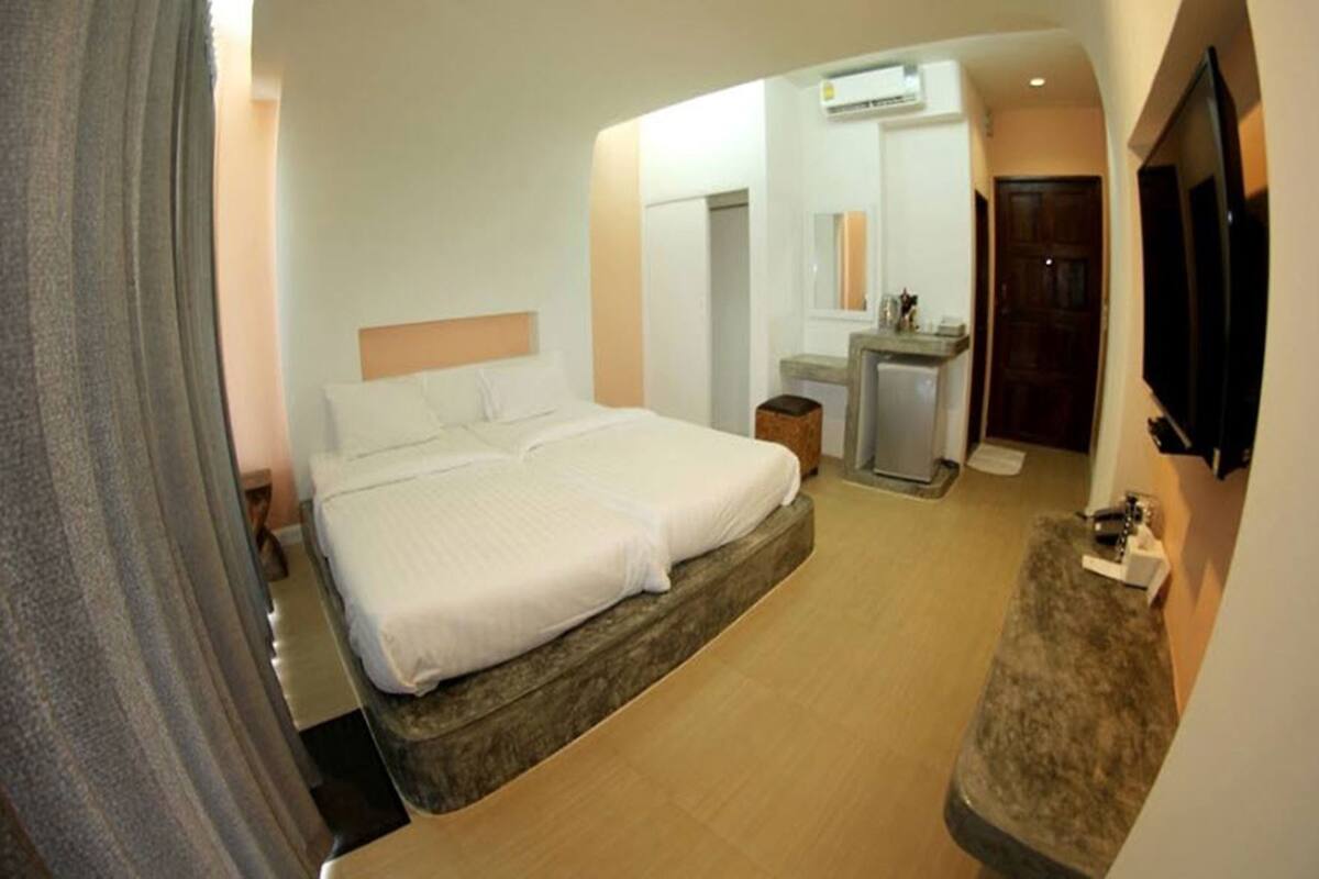 A hotel room with a large bed, a desk, a mirror, and a TV.