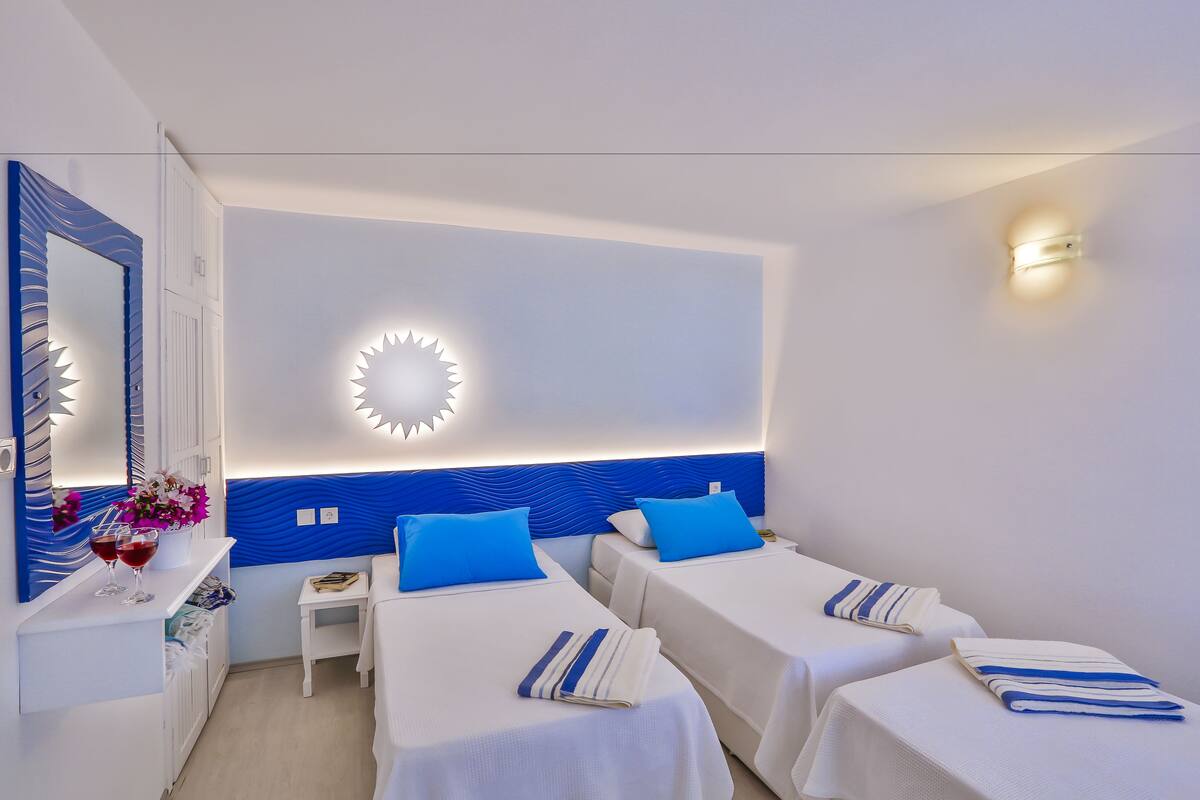 A hotel room with two beds, a vanity with a mirror, and a wall-mounted light fixture.