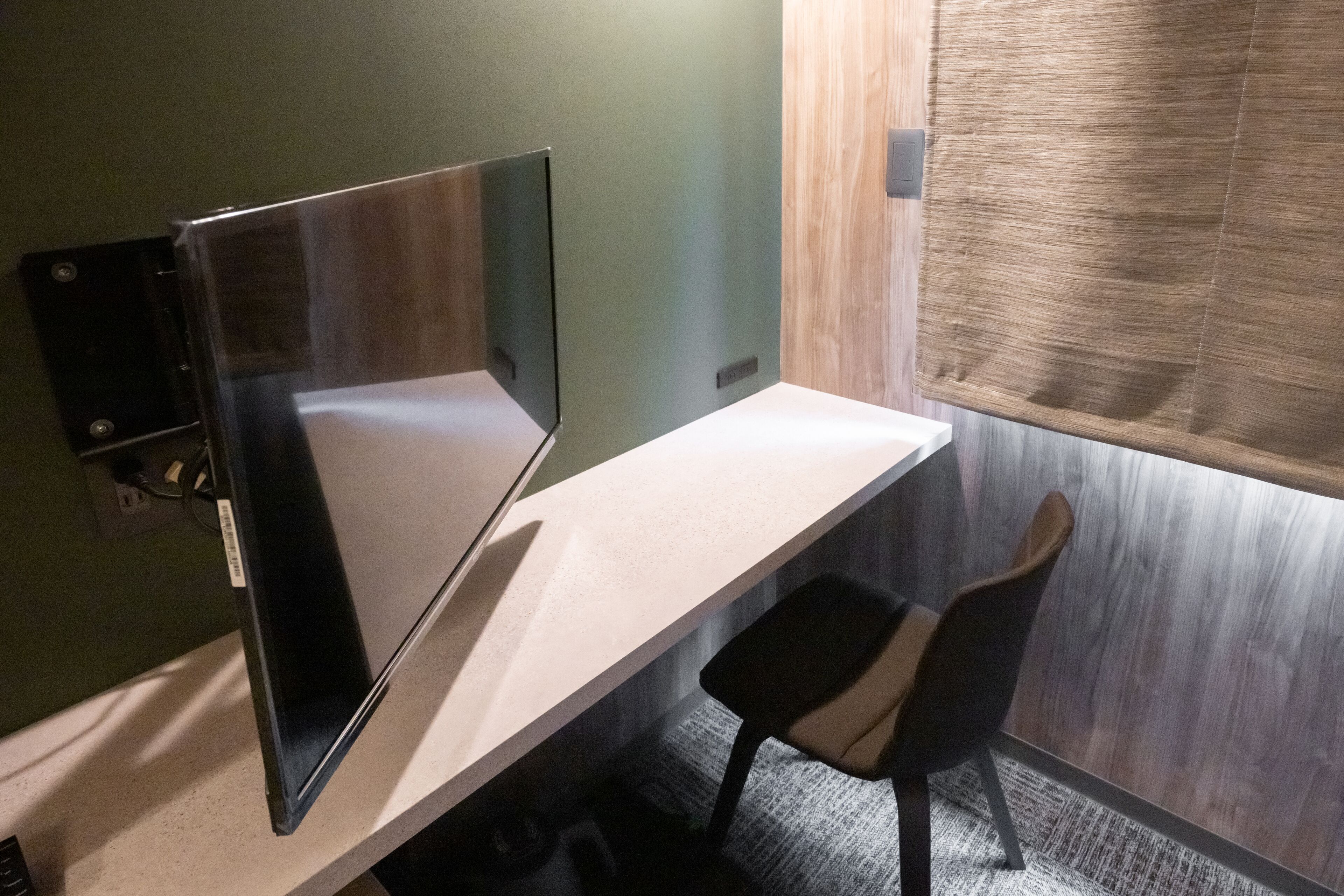 A modern office space with a desk, chair, and a window with blinds.