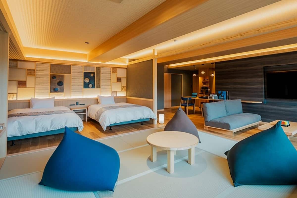 A modern hotel room with a bed, two sofas, a small table, and a TV.