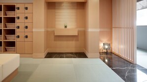 A modern hotel room with a built-in wardrobe, a small seating area with a plant, and a large window.