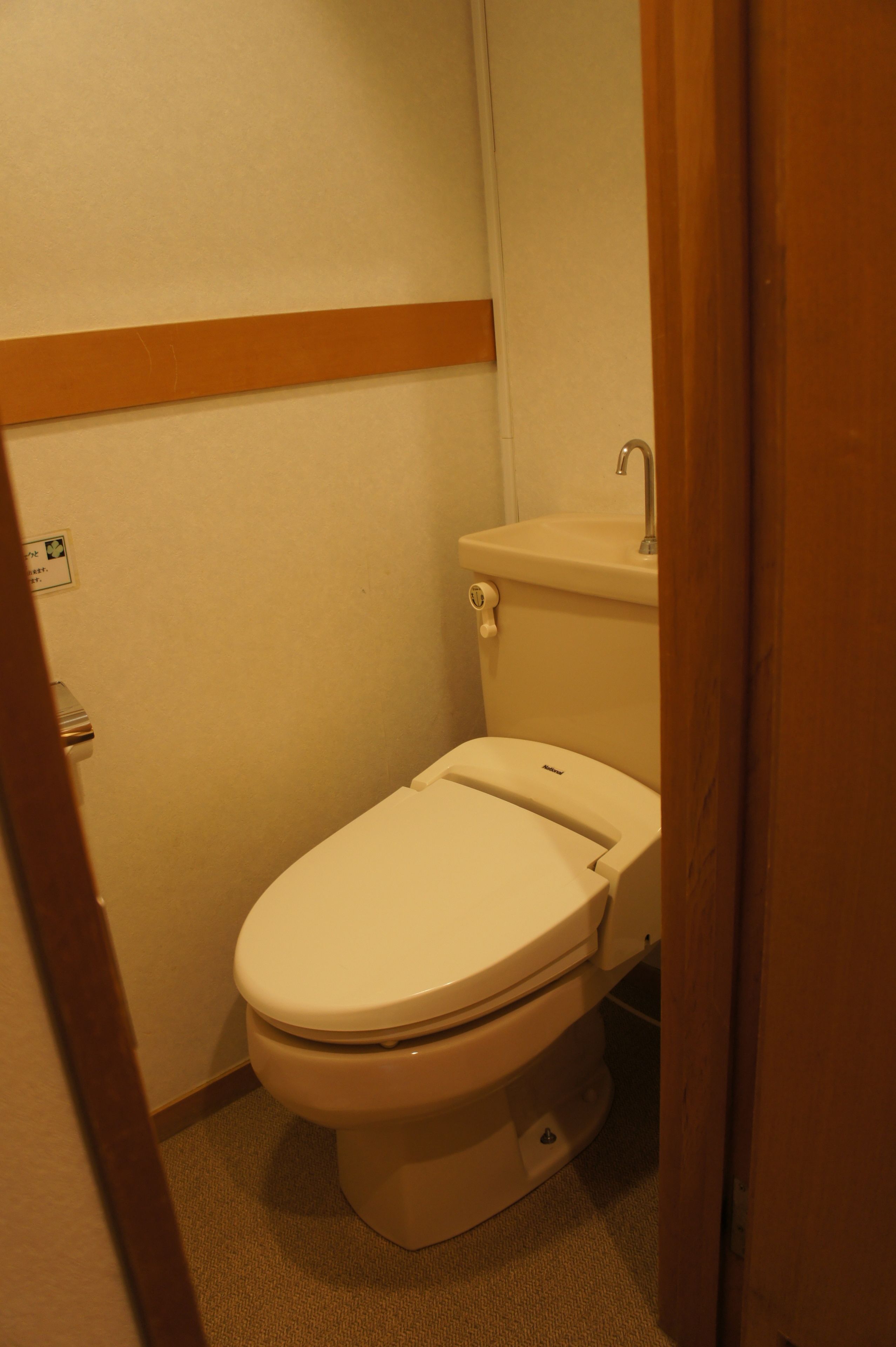 Un baño pequeño y funcional con inodoro, lavamanos y zócalo de madera.