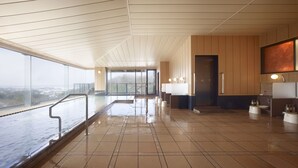 A spacious indoor area with a high ceiling, a large window overlooking a cityscape, and a wet floor indicating recent rain.