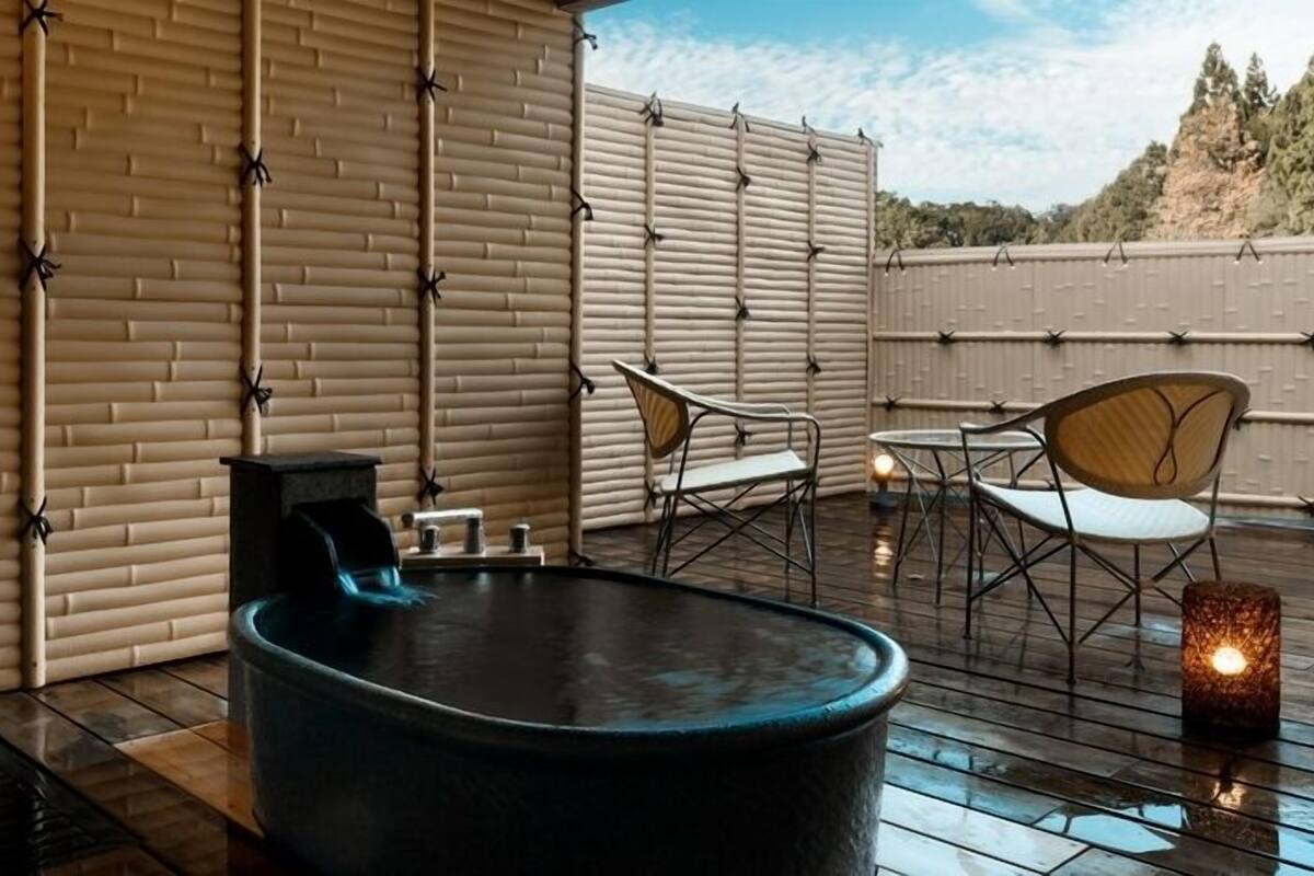 A rooftop terrace with a hot tub, seating area, and a candle.