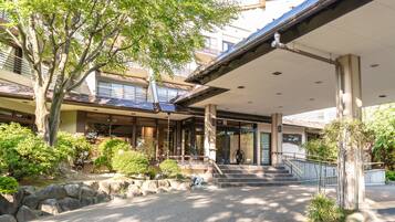 A traditional Japanese building with a covered entrance, stone steps, and surrounding greenery.