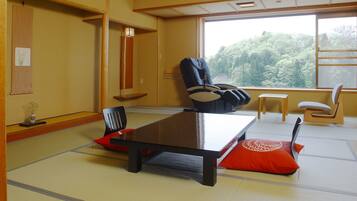 A tatami mat room with a low table, a black chair, and a red cushion.