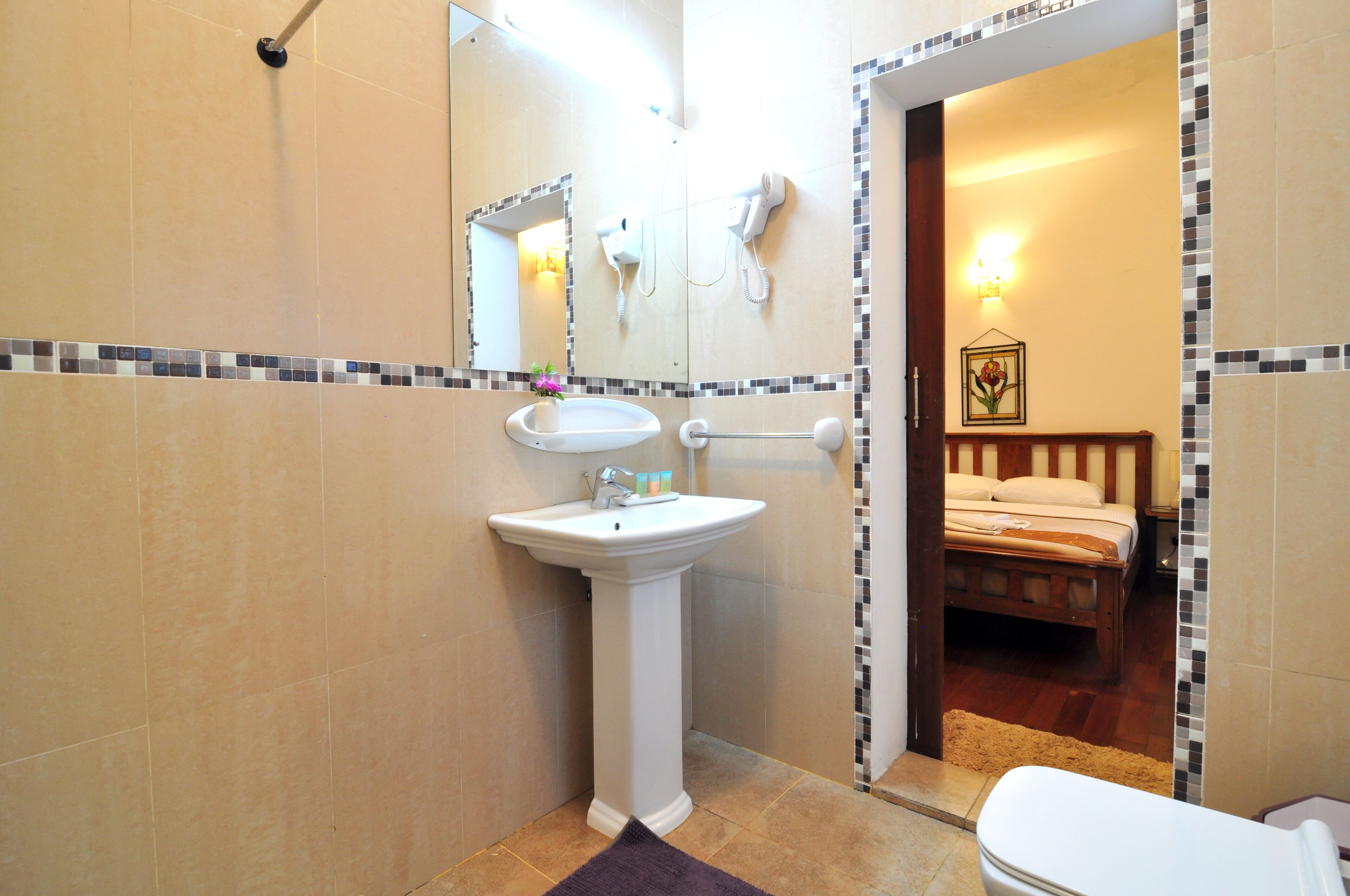 A bathroom with a pedestal sink, a hairdryer, and a mirror.