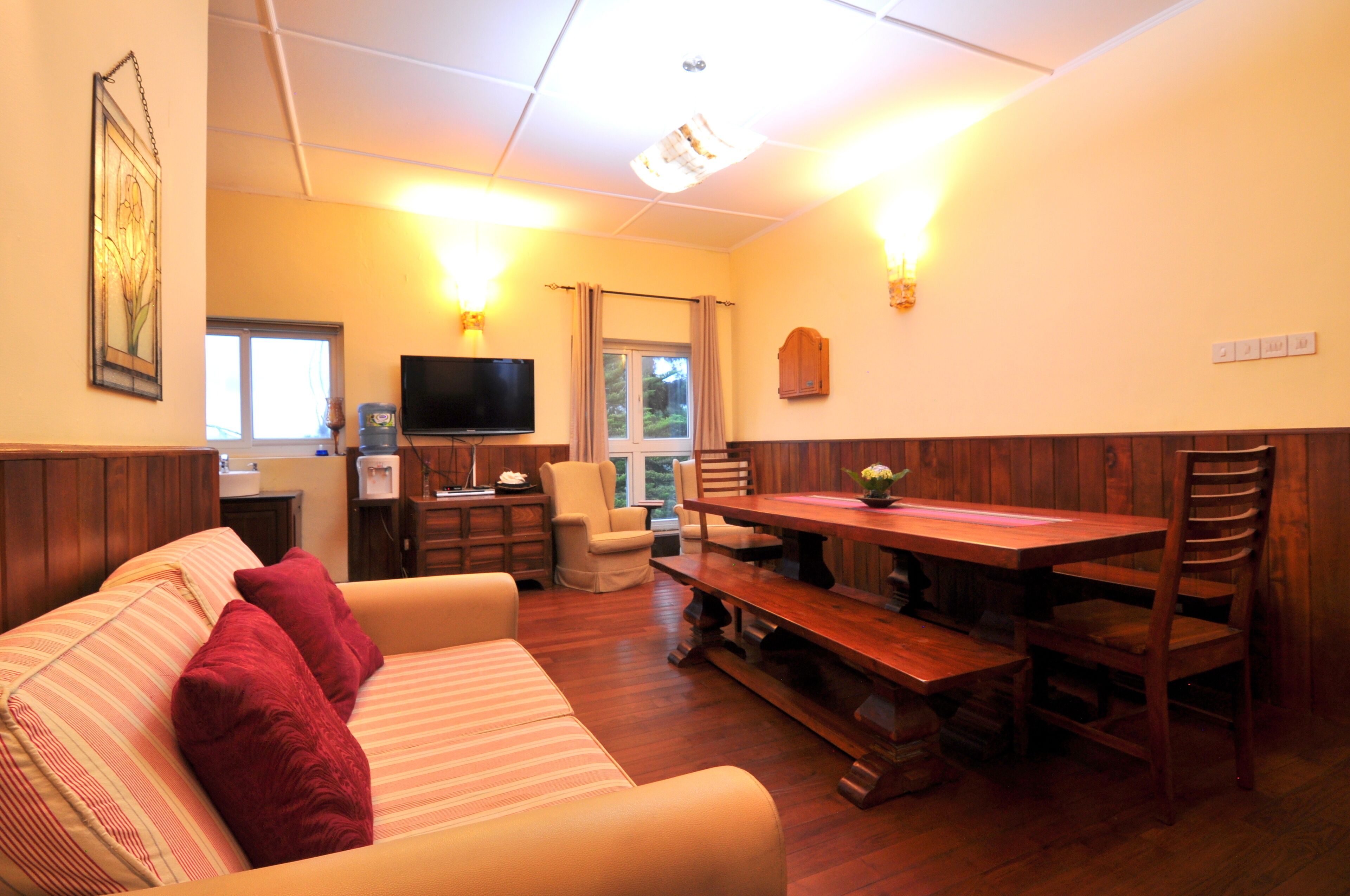 A cozy living room with a sofa, a wooden dining table, and a television.