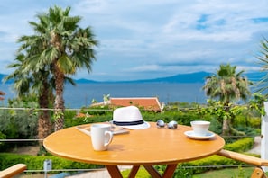 A round wooden table with a white cup, a white hat, and a pair of sunglasses on it.