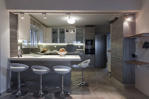Cozinha moderna com ilha central, banquetas e eletrodomésticos embutidos.