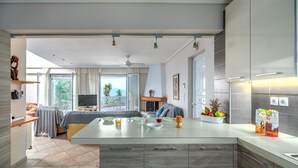 A modern kitchen with a large island, a dining area with a sofa, and a view of the outdoors.
