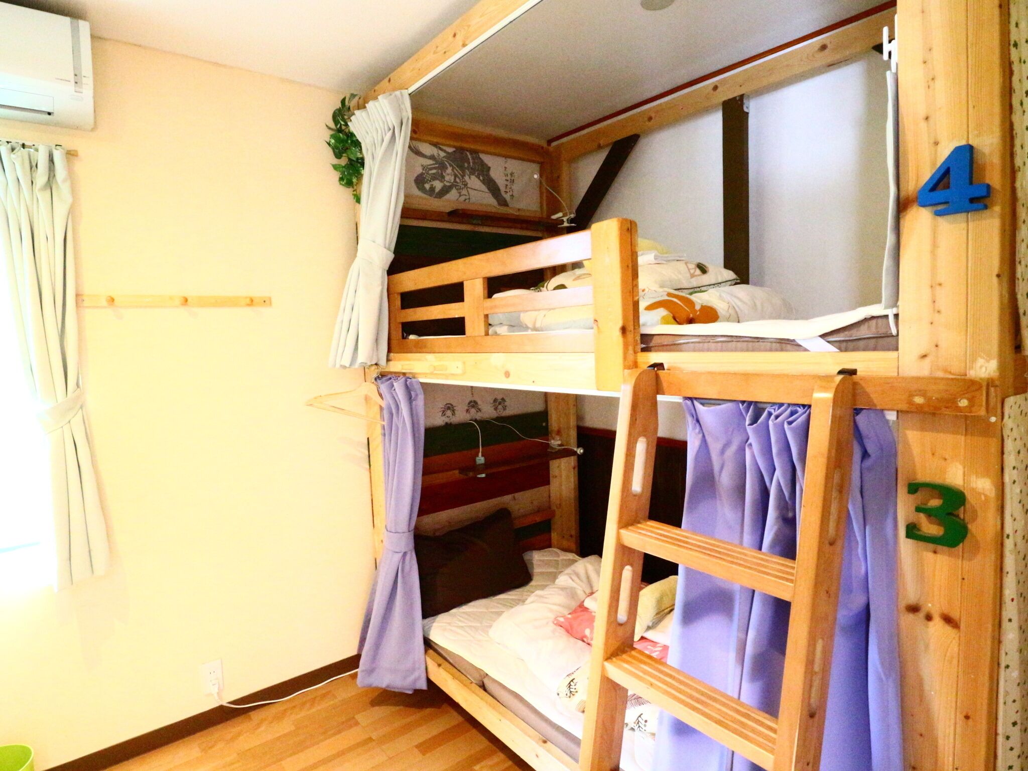 Habitación con literas de madera, una litera inferior con escalera, y el número 4 en la pared.