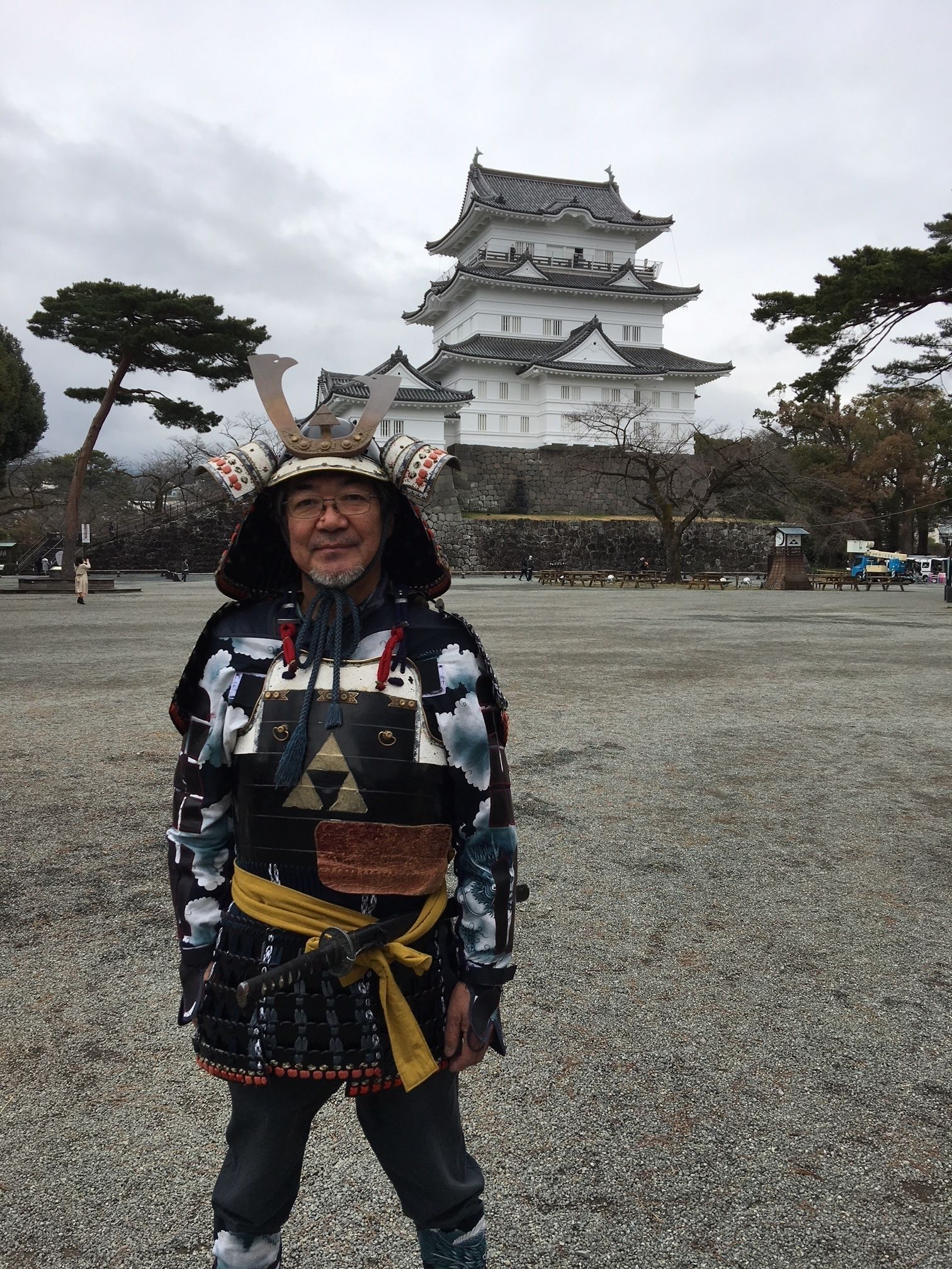 A person in traditional samurai attire standing in front of a castle.