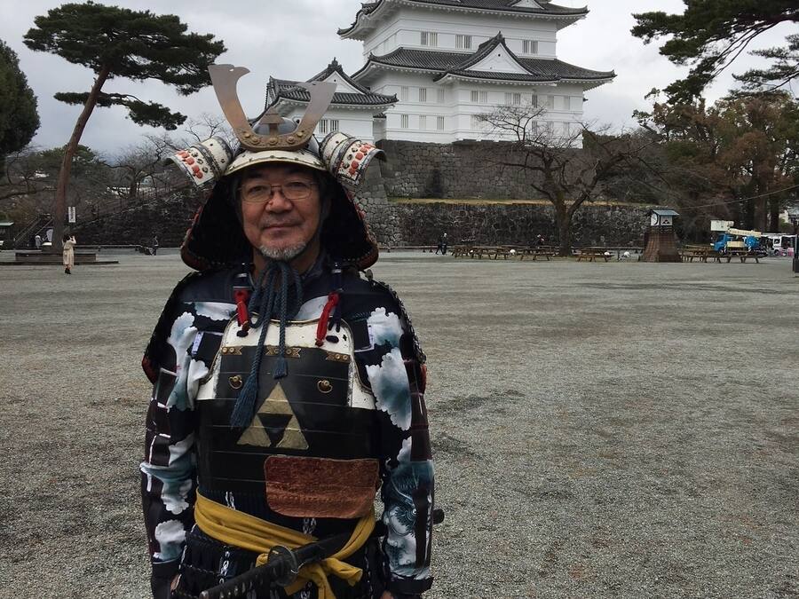 Eine Person in traditioneller Samurai-Kleidung vor einer Burg.