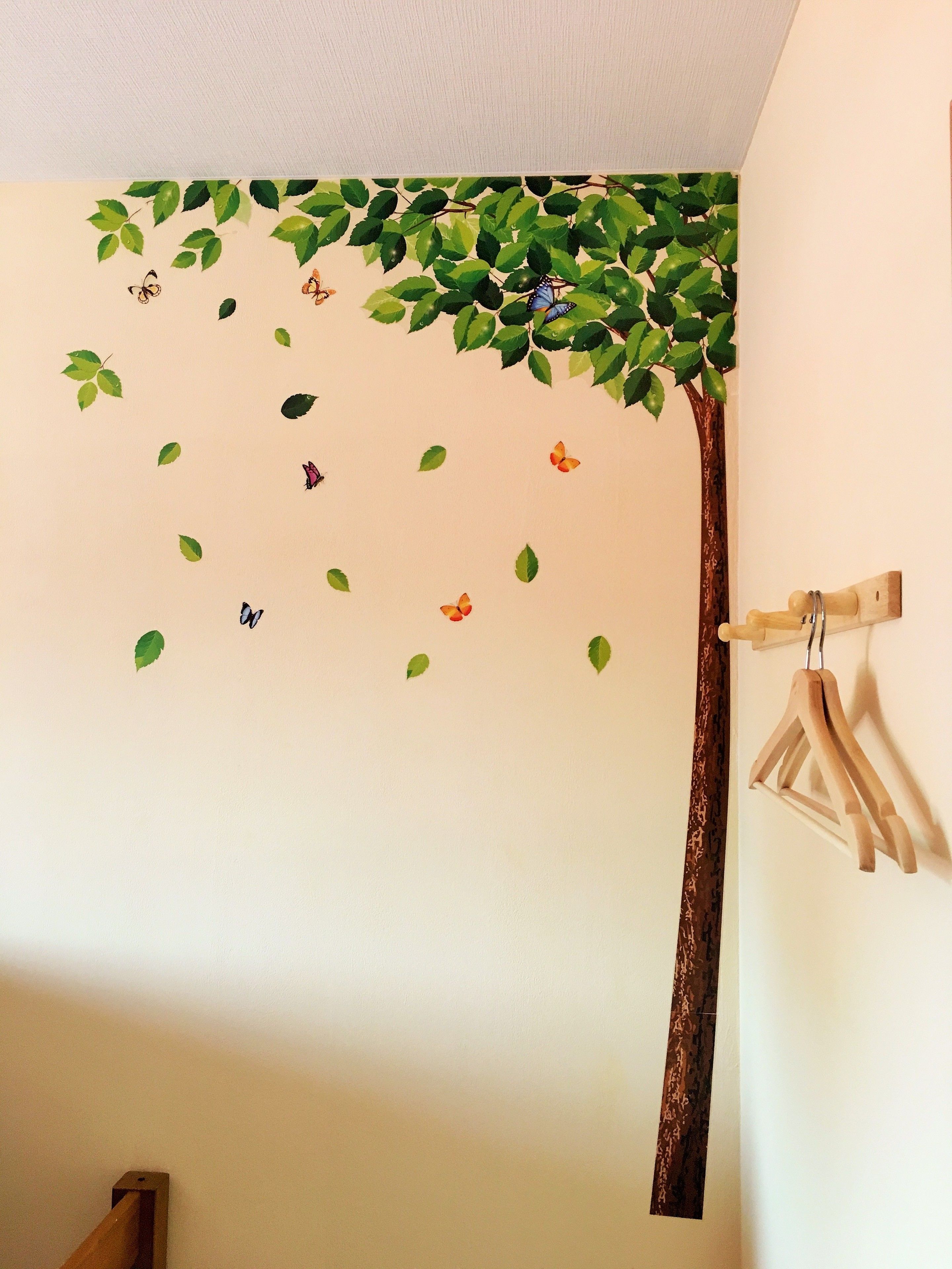 A wall with a tree decal, leaves, and butterflies.