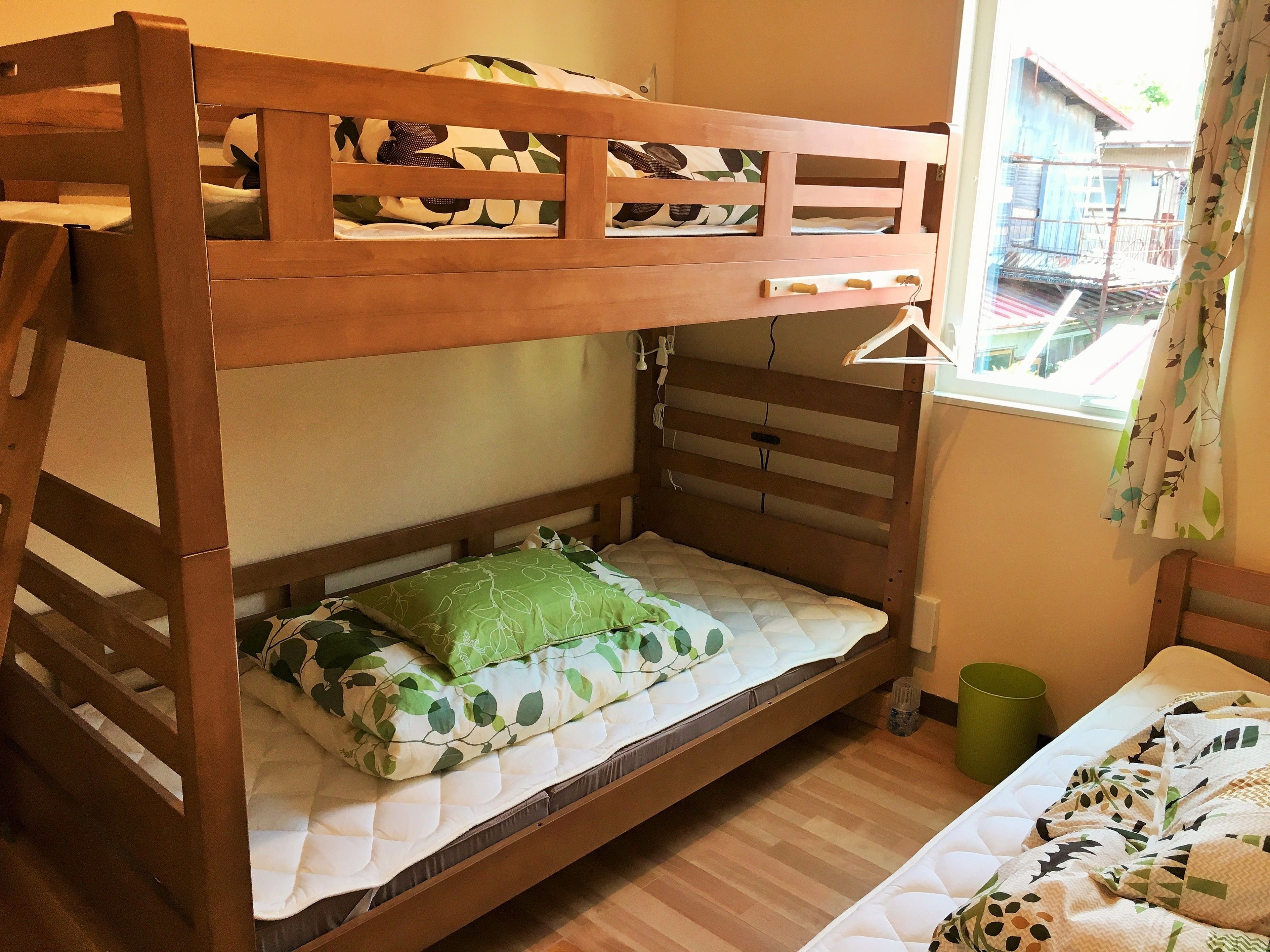 A bunk bed with a wooden frame, a green leaf-patterned pillow, and a white quilted mattress.