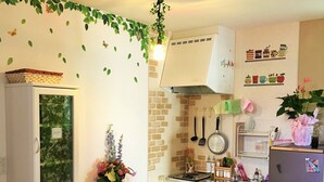 A compact kitchen with white cabinetry, a small dining table, and a refrigerator.