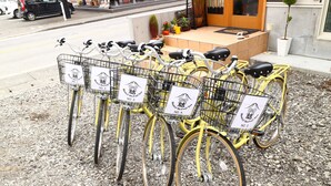 A row of yellow bicycles with baskets, each labeled with a number and a logo.