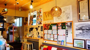 A cozy cafe with wooden interiors, a world map, and various informational posters on the walls.