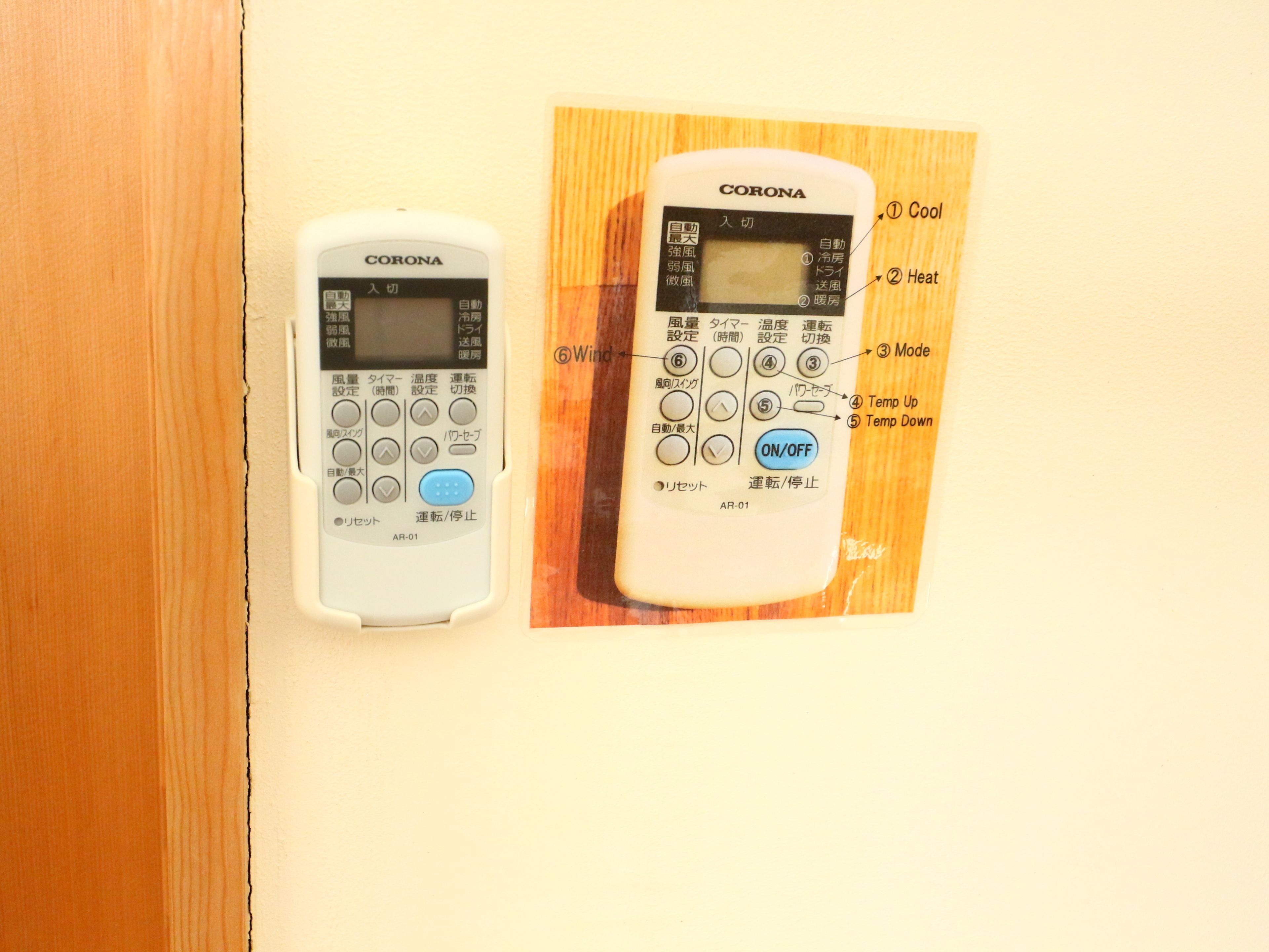 Two white Corona brand thermostats mounted on a wall, with labels indicating functions like 'Cool,' 'Heat,' and 'Mode.'