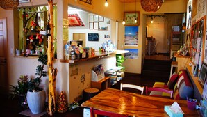 A cozy, well-lit room with a wooden table, chairs, and a variety of decorations including plants and framed pictures.