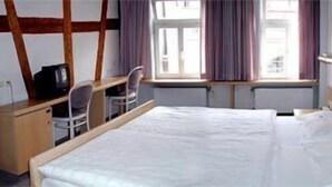 A hotel room with a bed, a desk, a chair, and a window with curtains. - Hotel Ratsstube Calw (Calw)