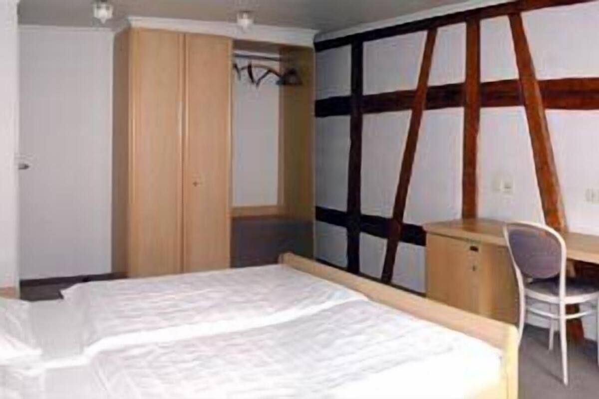Un dormitorio con cama, escritorio y silla. Hay un armario y una pared con diseño de madera.