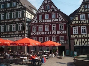 A traditional half-timbered building with outdoor seating and red umbrellas.