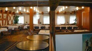 A dining area with round tables and chairs, wooden beams, and a chandelier. - Hotel Ratsstube Calw (Calw)