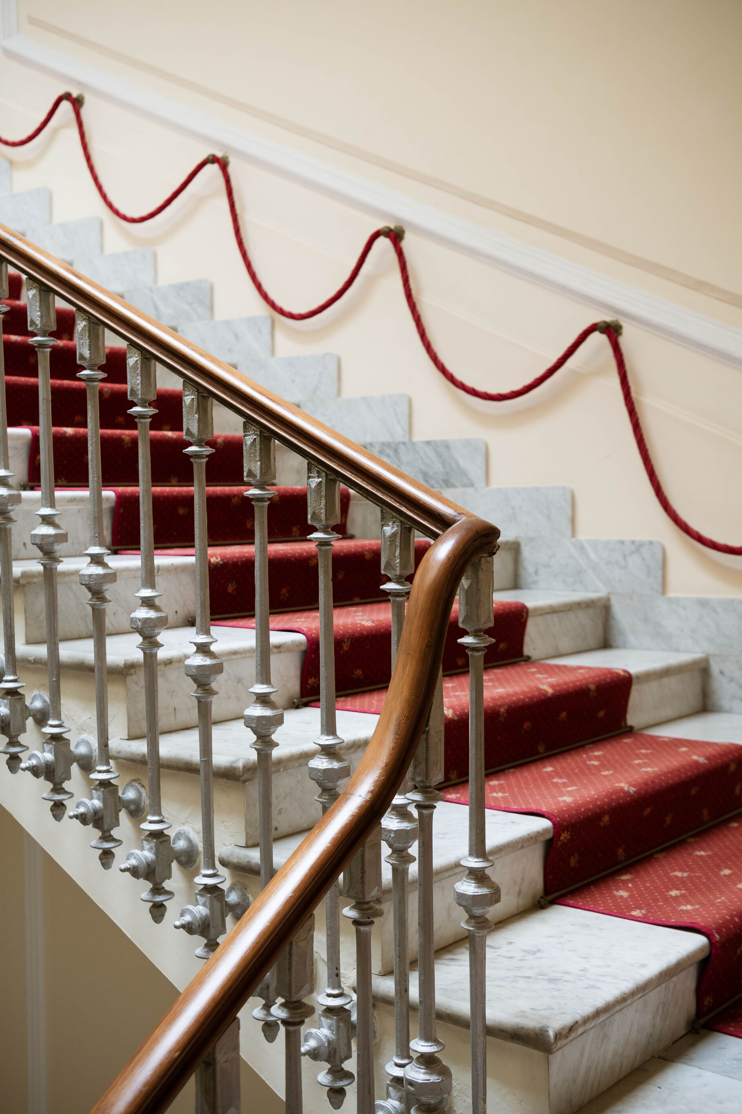 A staircase with red carpeted steps and a wooden handrail.
