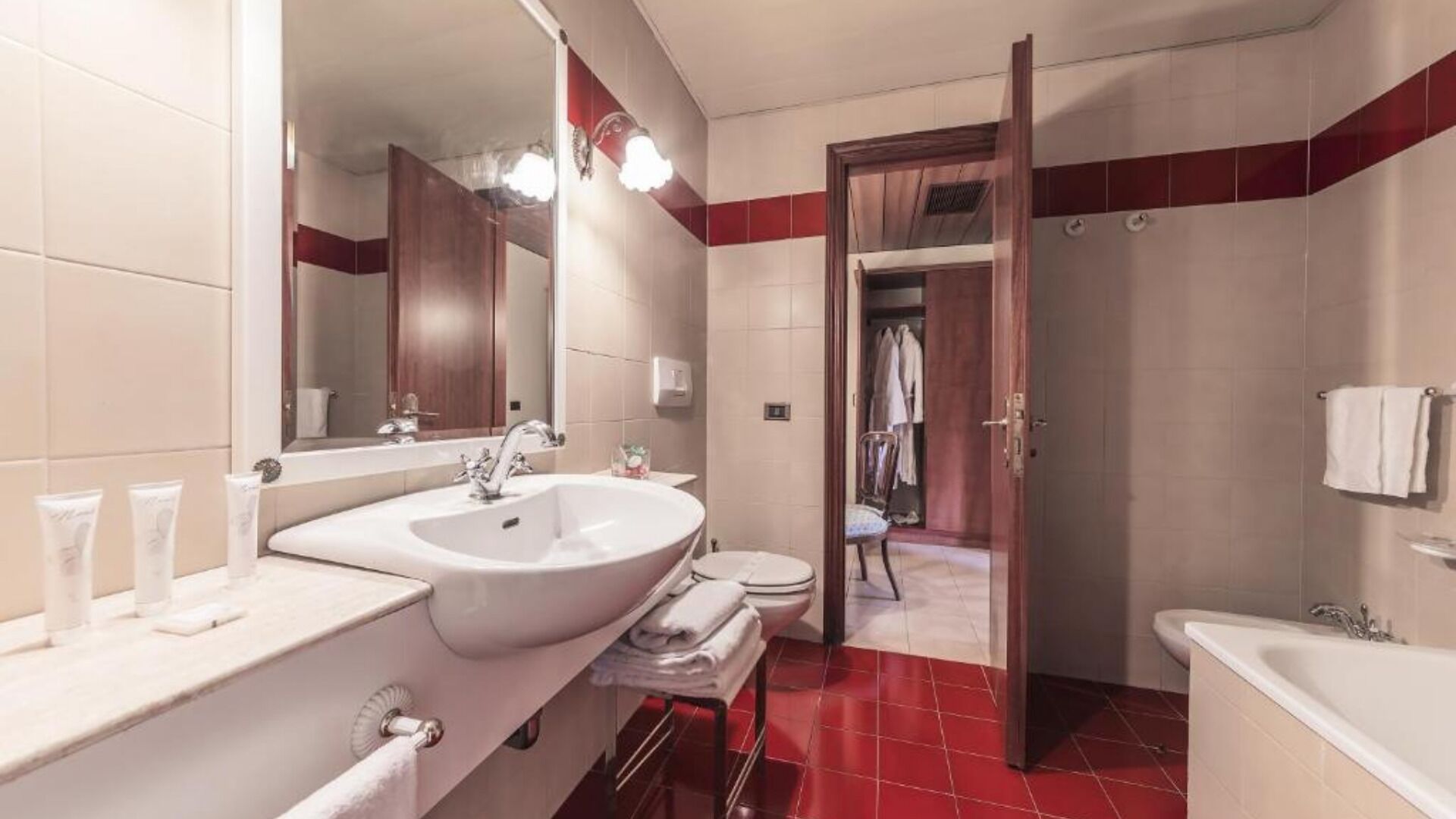 A modern bathroom with a large sink, mirror, and two toilets.