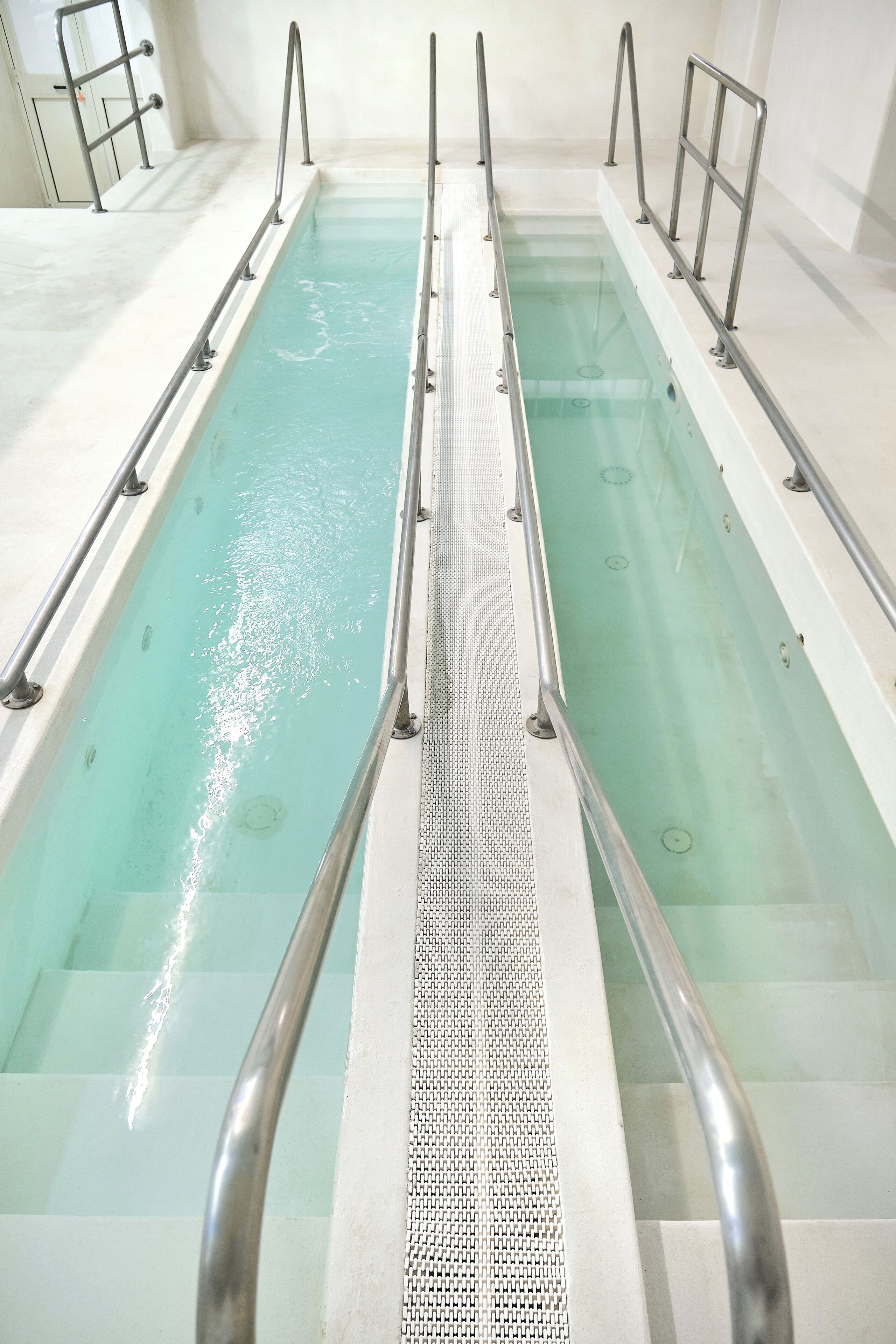 Ein Schwimmbecken mit Metallgeländern und einem strukturierten Gehweg.