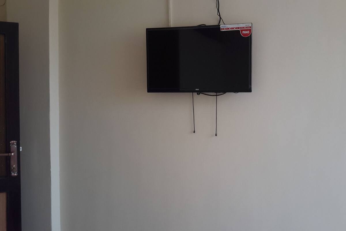 Televisão preta fixada numa parede lisa, com etiqueta da marca visível.