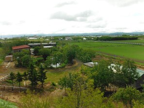 A rural landscape with a small building, a large water tank, and a fenced field.