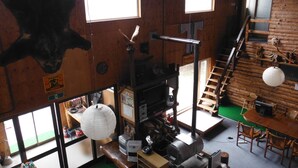 A rustic cabin interior with a wooden interior, a fireplace, a dining area, and a staircase. - Clione Camp Guest House (Shari)