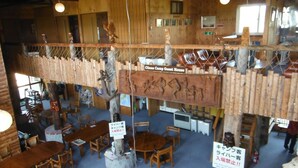 A rustic cabin interior with wooden furniture, a high ceiling, and a sign reading "Canoe Camp Guest House". - Clione Camp Guest House (Shari)