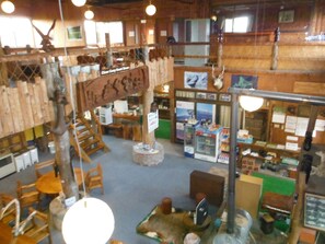 A rustic interior with wooden walls, a central wooden structure, and various seating arrangements.