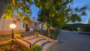 A building with a stone staircase leading to a porch, surrounded by trees and a paved driveway. - La Formichina (Peschici)