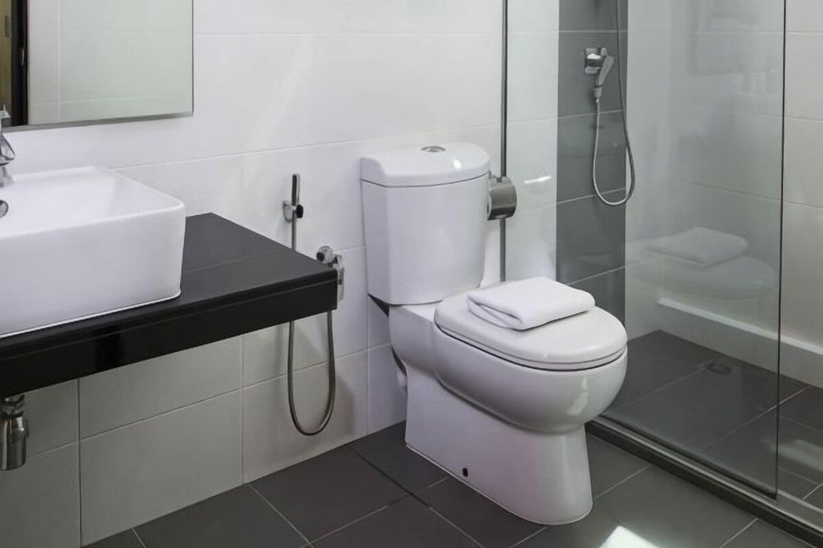A modern bathroom with a white toilet, a black countertop with a sink, and a glass-enclosed shower area.